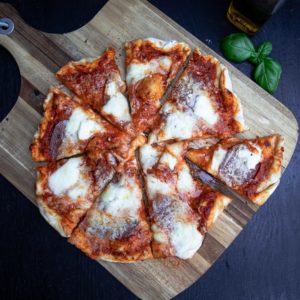 peperoni pizza auf brett mit balsamico blatt