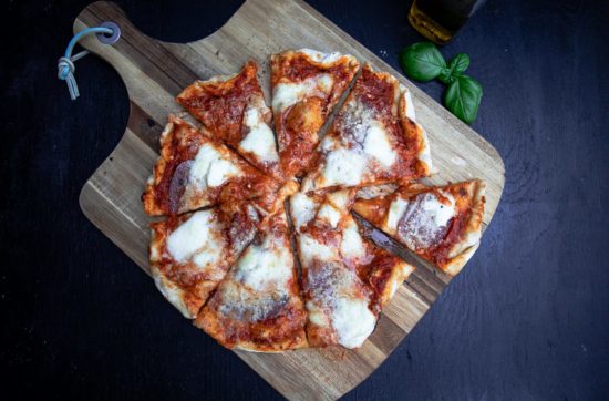 peperoni pizza auf brett mit balsamico blatt