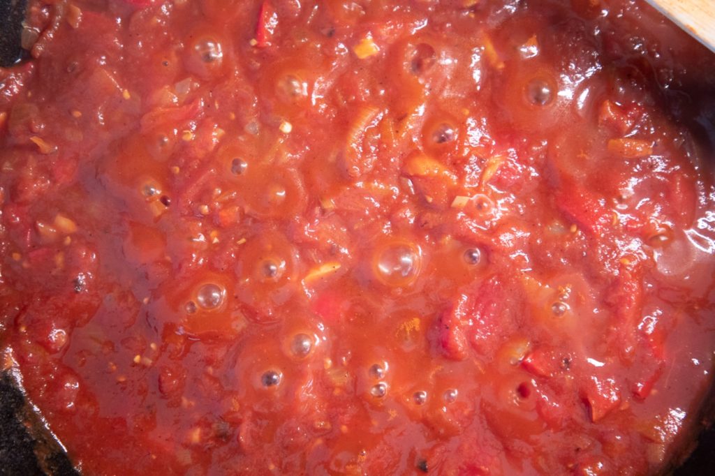 Tomatensauce, die für Shakshuka in der Pfanne köchelt